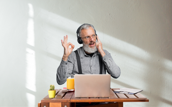 Older man with headphones giving an OK sign